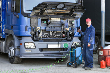 Mechanic repairing truck. Engine oil change.	
