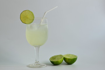 Lemon juice in wine glass on white background