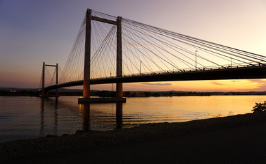 Obraz premium Cable-stayed bridge over river at sunset