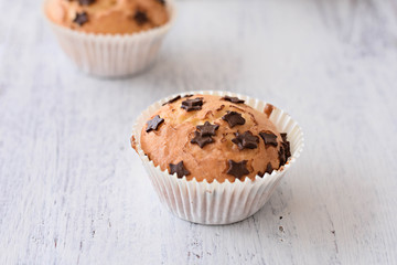 Sweet delicious homemade vanilla muffins whit chocolate chips at white wooden background
