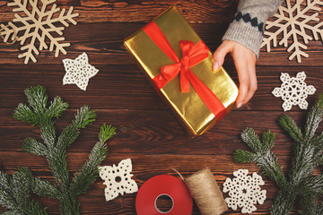 Woman holding wrapped Christmas present in her hands, view from above