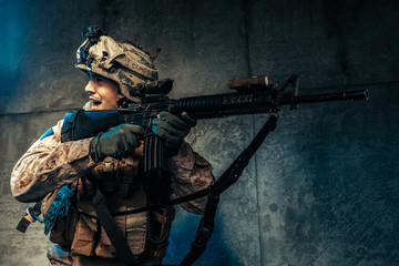 Naklejka premium Young man in military outfit a mercenary soldier in modern times on a dark background in studio