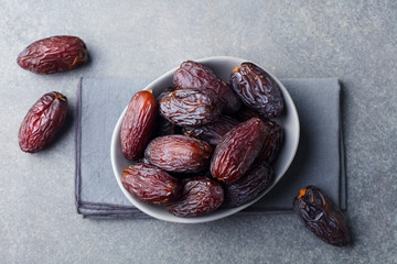 Fresh Medjool Dates in a bowl. Ramadan kareem. Grey stone background. Top view.