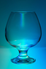 Empty transparent glass goblet in multicolored light