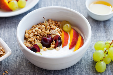 Healthy breakfast. Fresh granola, muesli with yogurt, fruits and berries on grey background. Close up.