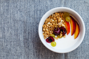 Healthy breakfast. Fresh granola, muesli with yogurt, fruits and berries on grey background. Top view. Copy space.