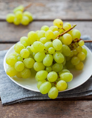 Grape on a white plate. Grey wooden background. Close up.