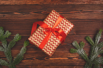 Stylish decorated Christmas gift with ribbon on wooden background, top view