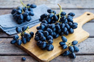 Fresh grape on cutting board. Grey wooden background. Close up.
