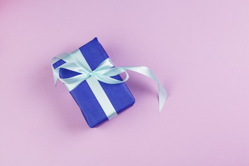 Top view of a decorated present with a bow on pink background
