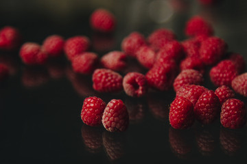 berries of red raspberries in a bunch lie on a black glass top view. sweet summer berries