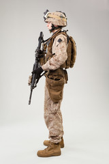 Soldier in US marines uniform with rifle on light grey background, studio shot