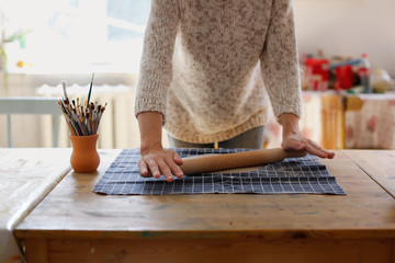 rolling clay with rolling pin on fabric on table