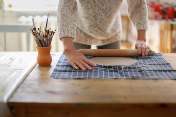 rolling clay with rolling pin on fabric on table