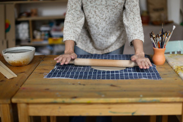 rolling clay with rolling pin on fabric on table