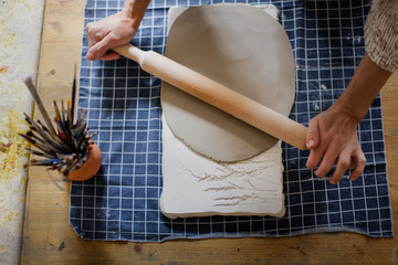 rolling clay with rolling pin on fabric on table