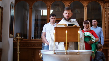 The sacrament of baptism. Christening the baby. Child, priest and parishioners.