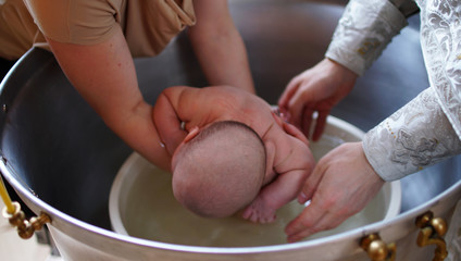 The sacrament of baptism. Christening the baby. Child, priest and godfather.