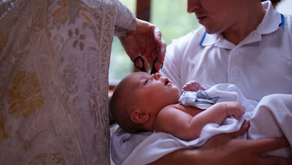The sacrament of baptism. Christening the baby. Child, priest and godfather.