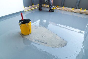 construction worker renovates balcony floor and spreads watertight resin and glue before chipping and sealing
