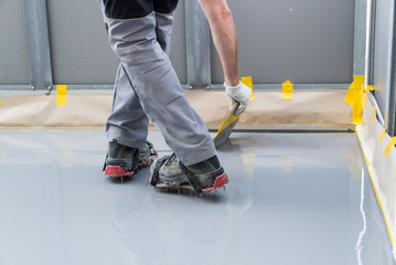 construction worker renovates balcony floor and spreads watertight resin and glue before chipping...