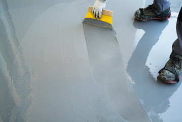 construction worker renovates balcony floor and spreads watertight resin and glue before chipping...