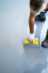 construction worker renovates balcony floor and spreads watertight resin and glue before chipping and sealing