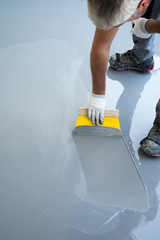 construction worker renovates balcony floor and spreads watertight resin and glue before chipping...