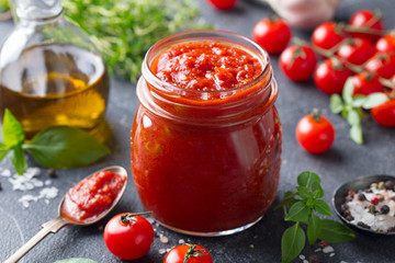 Tomato sauce in a glass jar with fresh herbs, tomatoes and olive oil. - 289641242
