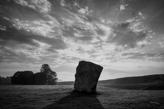 Stunning  black and white Summer sunrise landscape of Neolithic standing stones in English cluntryside with gorgeous light with slight background mist
