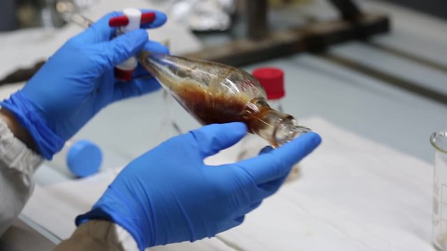 scientist hands shaking a separating funnel with a liquid extract