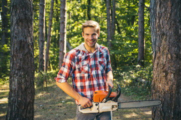 Man doing mans job. Happy Woodworkers lumberjack. Lumberjack with chainsaw on forest background....