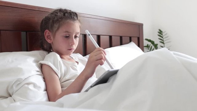 Child in bed drawing with tablet PC