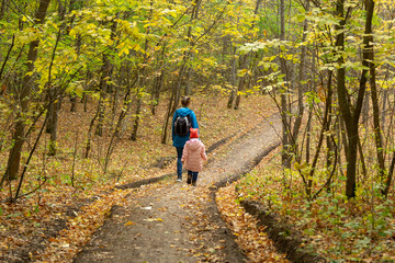 Fototapeta premium Mother and daughter are walking in the autumn forest