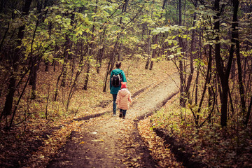 Mother and daughter are walking in the autumn forest