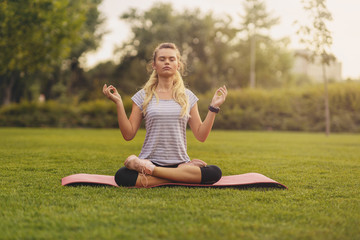 Young Woman practicing yoga pose at the city park at sunset - Concept for Yoga Sport and Healthy lifestyle