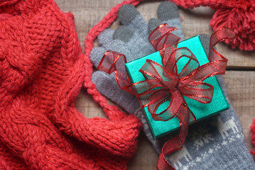 Fototapeta na wymiar Close up green gift box on gray glove near red yarn winter hat with background wood table.