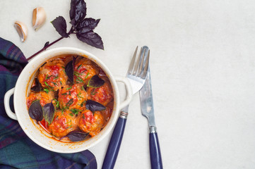 Meatballs stewed in tomato sauce in a saucepan with basil and garlic