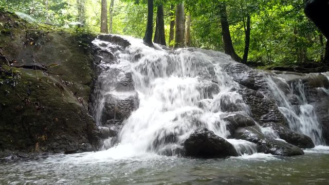 Motion timelapse move from top to the ground in sunny day front view of beautiful waterfall in tropical forest Sa Nang Manora National Park in Phang-nga Province , forest park in southern Thailand. 