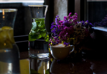 Beautiful glass pitchers with mint, water and fruits. Dishes in the café. Dark background. Cups and glasses.