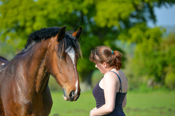 Portrait of a woman and her horse loose in a field.