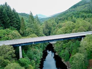 Aerial view of a bridge crossing a river in the middle of a forest 