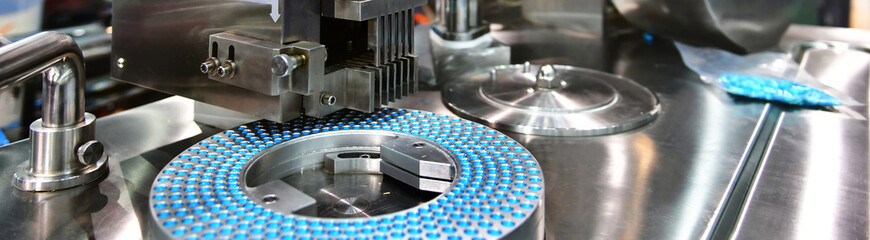 Blue capsule medicine pill production line, Industrial pharmaceutical concept.banner size	