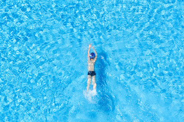 Top view of a boy swimming in an outdoor pool.