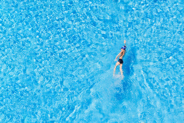 Boy swimming in the pool outdoors, top view.