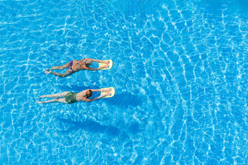 Two women swimming in the pool on a sunny day.