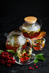 Tea from viburnum and forest herbs. Hot winter drinks. On a black background. Top view.