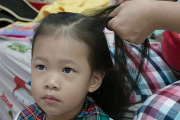 Mother doing hair for baby girl at home