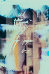 Reflection in a window glass of woman which is using mobile phone. Real people, authentic situations
