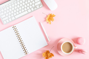 Autumn office composition. Women's office desk. Dried leaves, notebook, keyboard, cup of coffee, macaroon on pastel pink background. Fall concept. Autumn background. Flat lay, top view, copy space
